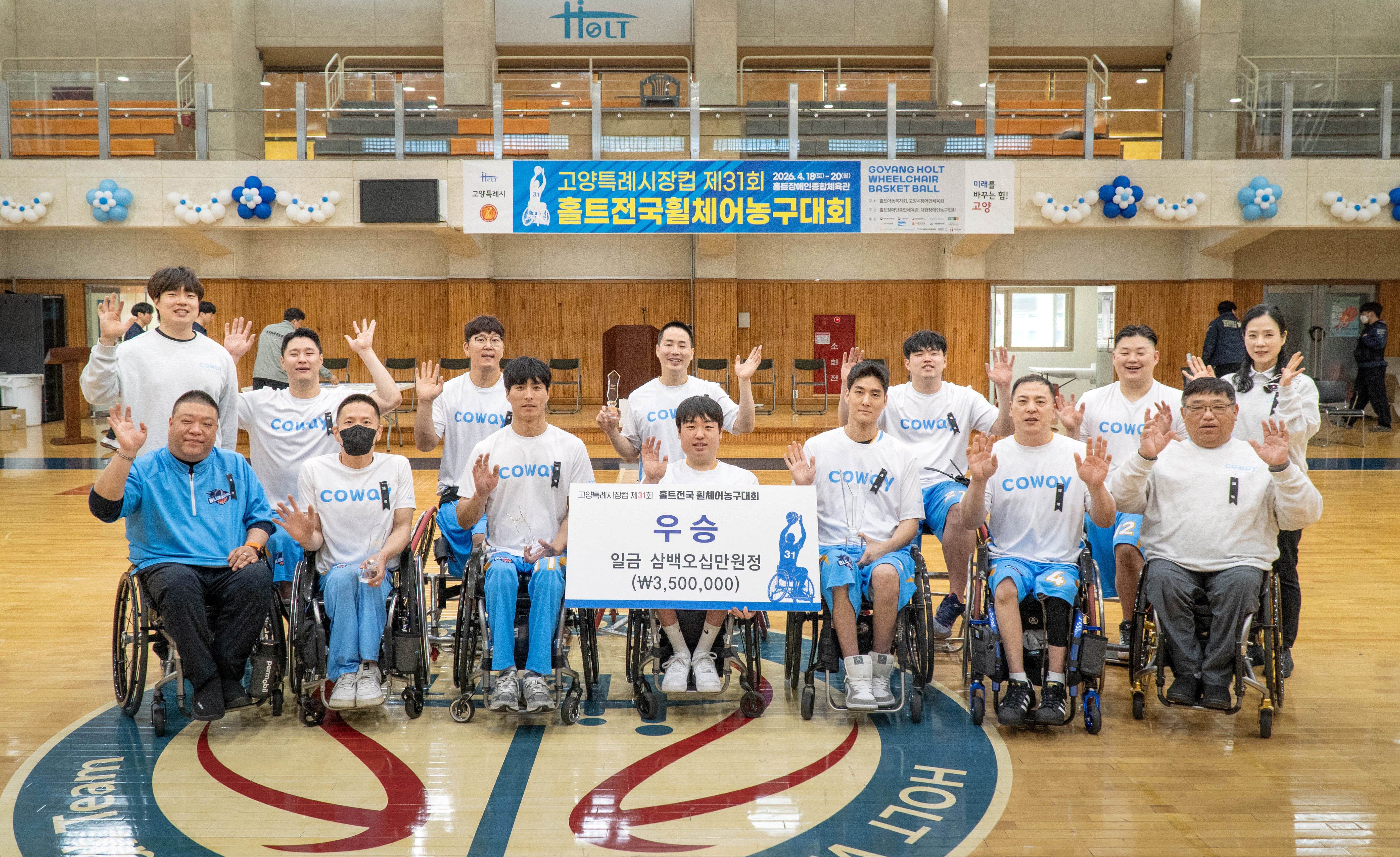 '제31회 홀트전국휠체어농구대회'에서 우승을 차지한 블루휠스 휠체어농구단의 기념사진. 2026년 4월 20일 고양시 홀트장애인종합체육관 농구 코트 중앙에서 블루휠스 선수 및 관계자들이 승리의 기쁨을 나누고 있다.
