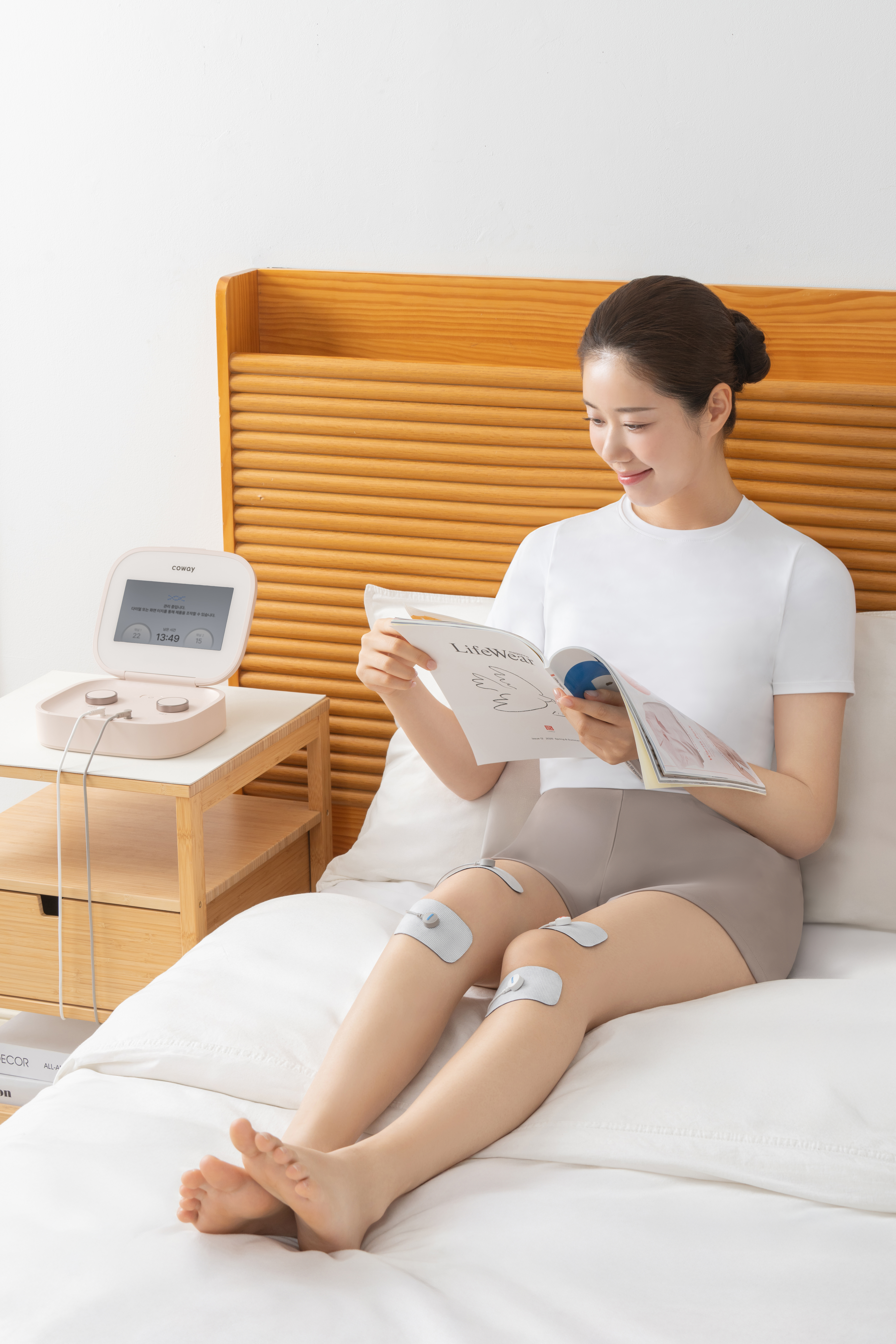 침실에서 휴식을 취하며 무릎에 전극 패드를 부착해 통증을 관리하는 식약처 인증 개인용 저주파 자극기 '테라솔 P'의 사용 모습입니다. 저주파 등 다양한 전기자극과 온열 요법을 결합한 TENS·EMS·온열 기술로 만성 및 근육 통증, 생리통, 난치성 통증 완화를 돕고, 가정에서 간편하게 활용할 수 있는 특징을 직관적으로 보여줍니다